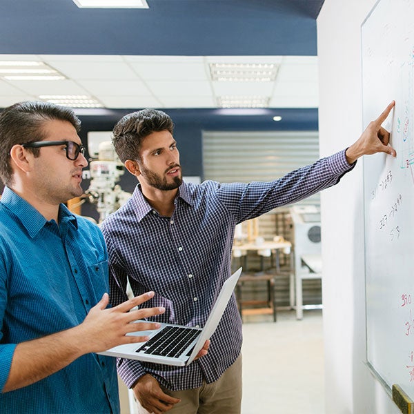 two men pointing at white board